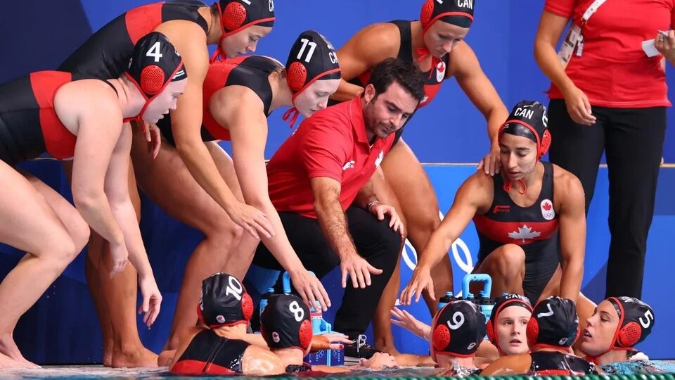 Les joueuses sont rassemblées sur le bord de la piscine avec leur entraîneur.