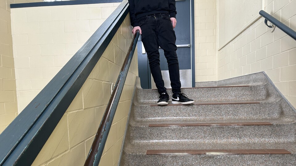 Un jeune debout sur des marches d'escalier.