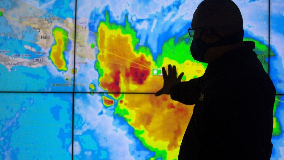 Un employé montrant une carte satellite de la tempête.