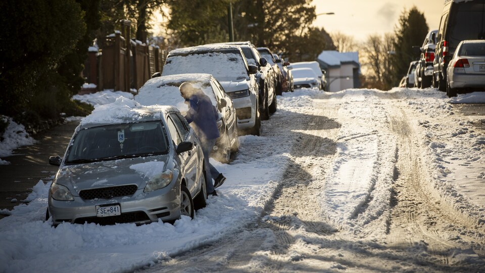 Un homme déblaie la neige accumulée sur sa voiture au lendemain d'une tempête à Vancouver, le mercredi 30 novembre 2022.