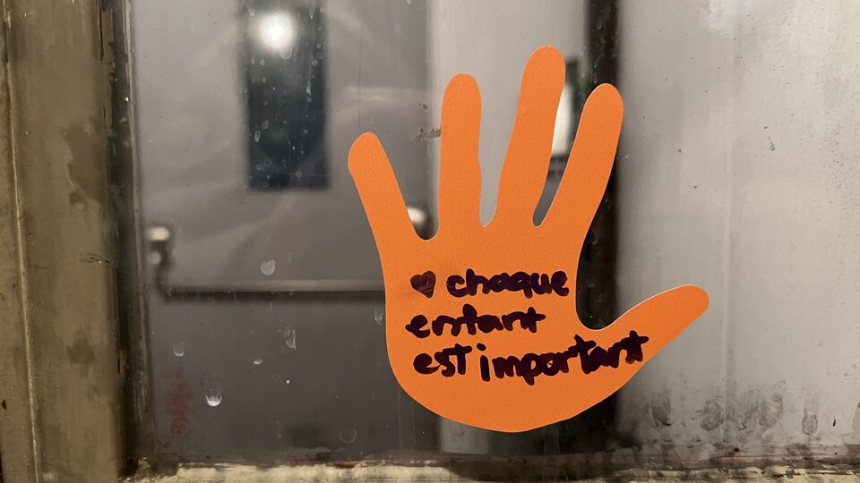 Une main découpée dans du carton est collée sur une fenêtre. Il est écrit : Chaque enfant est important.