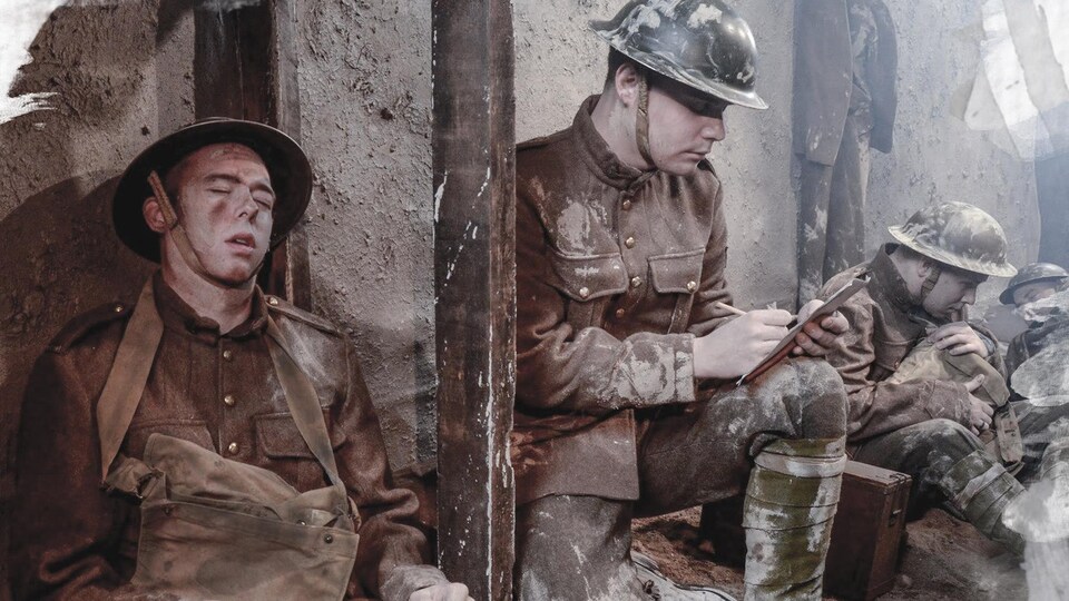 Dans une tranchée, un soldat somnole alors que son collègue à ses côtés écrit dans son calepin. 