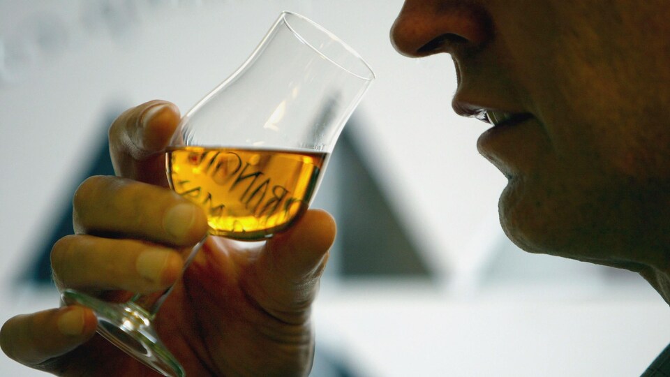 Un homme s'apprête à boire une gorgée de son verre de whisky.