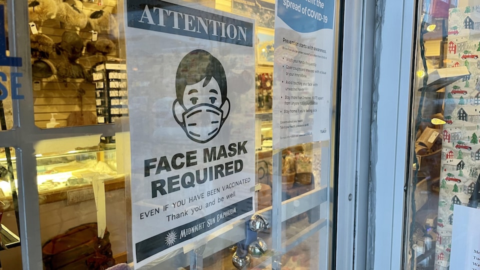 Une affiche indiquant que le port du masque est obligatoire à l'intérieur est collée sur la porte d'un magasin de souvenirs de Whitehorse.