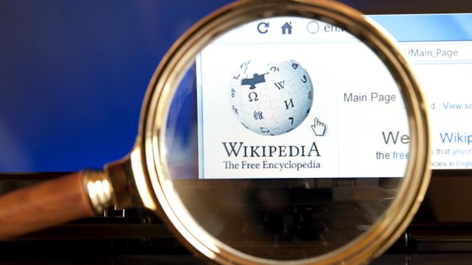 Le site Internet de Wikipédia avec une loupe grossissante.