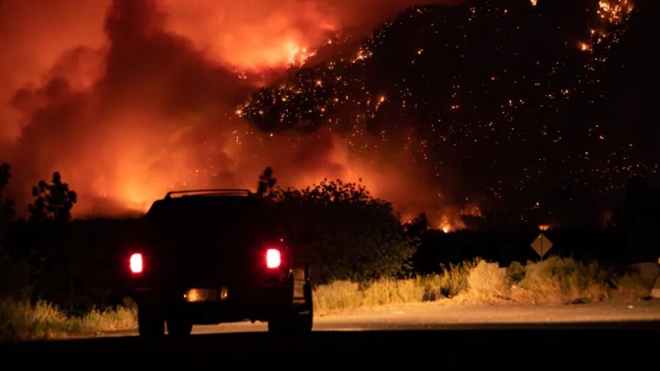 Un véhicule devant un important feux de forêt.