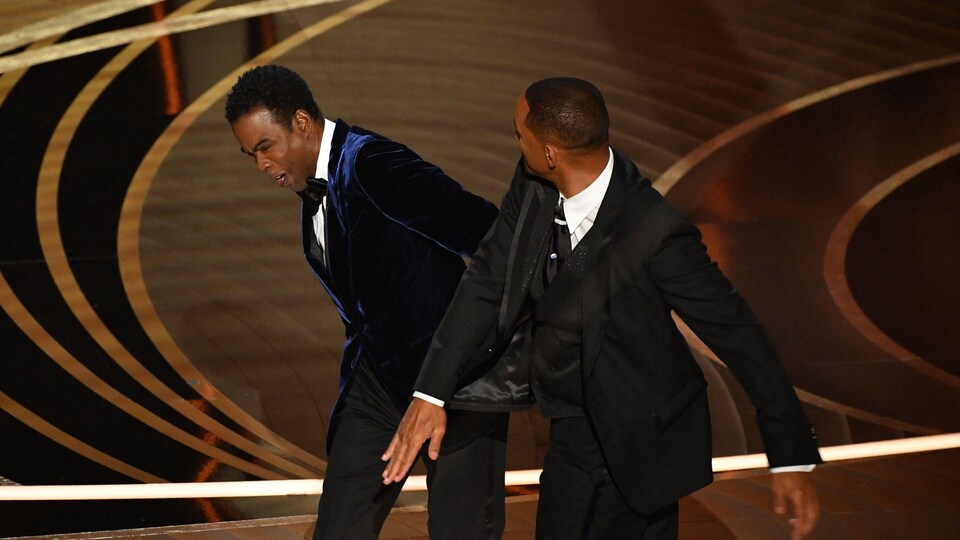 Un homme donne une gifle à un autre homme sur scène pendant une cérémonie des Oscars.