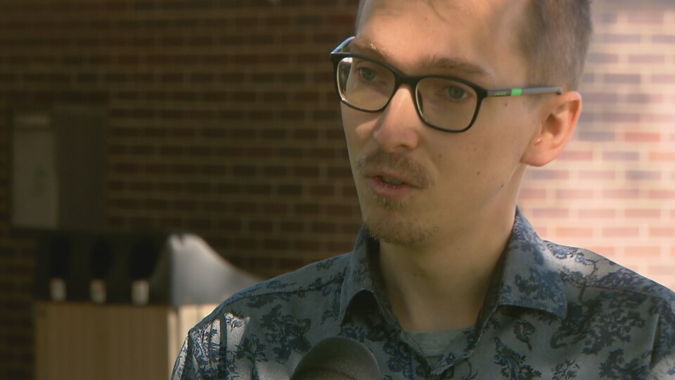 Un jeune homme portant une barbe récente et des lunettes