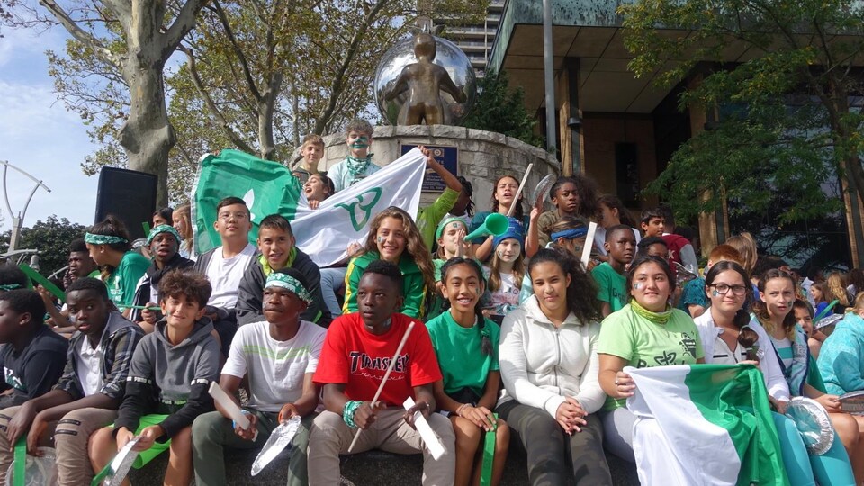 Une centaine de jeunes sont assis autour d'une fontaine et sont vêtus de vert et blanc, à Windsor.