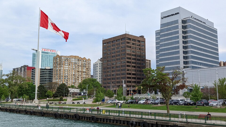 Des gratte-ciels vus de la rivière avec un grand drapeau du Canada.