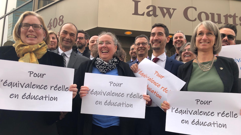 un groupe de francophones brandit des pancartes où on lit "pour l'équivalence réelle en éducation" devant la Cour d'appel du Manitoba.