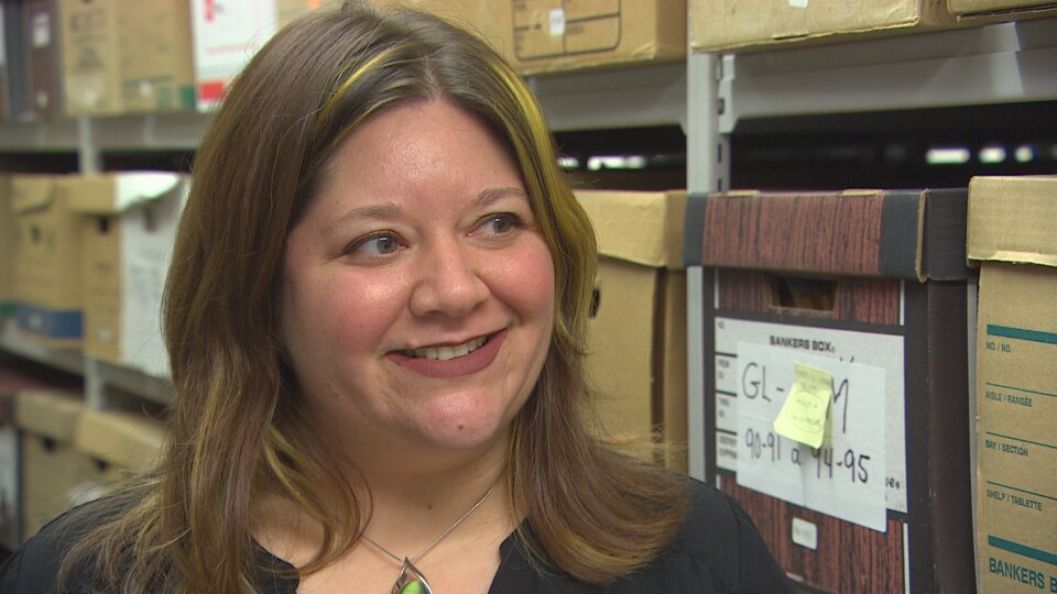 Portrait de Sarah Story au milieu de cartons d'archives.