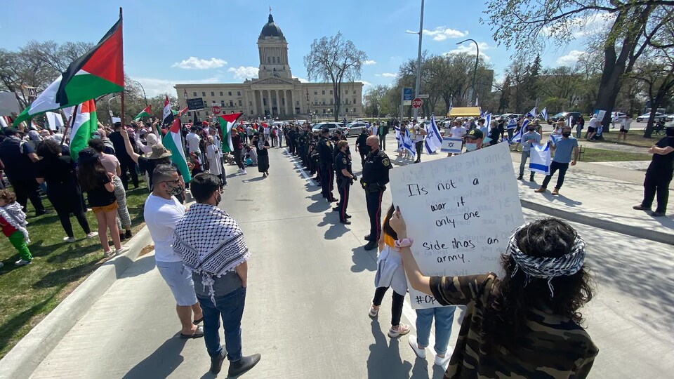 Les groupes de manifestants pro-Israël et pro-Palestine sont séparés par une douzaine de policiers.