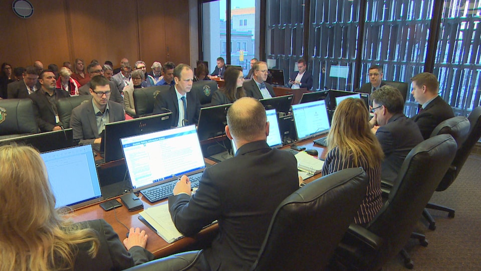 Les membres du comité exécutif de la Ville de Winnipeg dans une salle de réunion devant un public.
