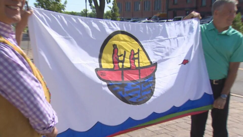 Un drapeau autochtone montrant 2 personnes dans une embarcation à rames.