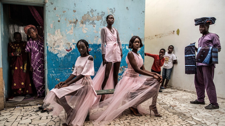 Trois femmes portent les tenues de la créatrice Adama Paris, dans le quartier de la Médina de Dakar, la capitale sénégalaise, sous le regard des habitants.