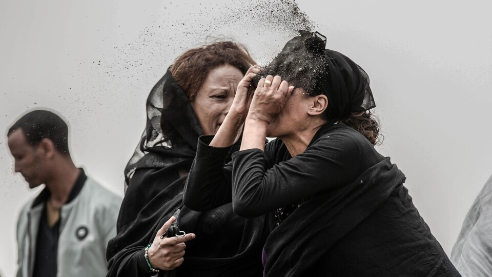 Une proche d’une victime de l'écrasement d’avion du vol ET302 d’Ethiopan Airlines, en habits de deuil, se lance de la terre au visage sur le lieu de l'écrasement.