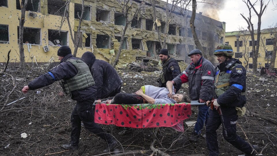 Une femme enceinte blessée est portée par des secouristes devant un hôpital ukrainien.
