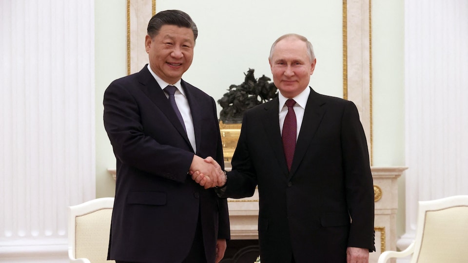 Xi Jinping et Vladimir Poutine se serrent la main en souriant.