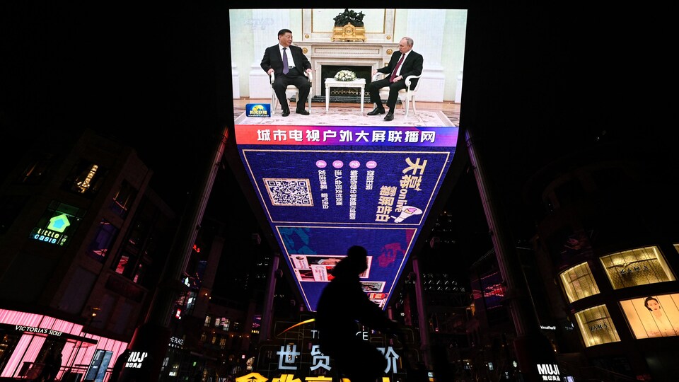 Un écran dans une place publique de Pékin diffuse une couverture en direct de la rencontre entre le président chinois Xi Jinping et le président russe Vladimir Poutine lors d'une visite d'État à Moscou, le 21 mars 2023.