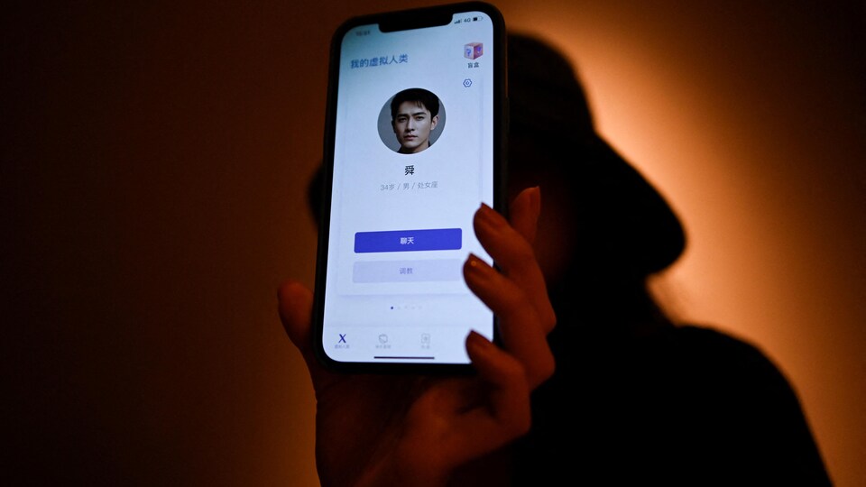 La femme dans l'ombre tient un téléphone intelligent avec la photo d'un jeune homme.