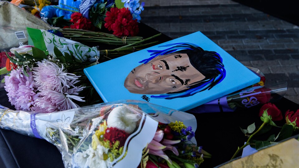Des fleurs et une illustration représentant le rappeur décédé XXXTentacion ont été déposées sur un trottoir.