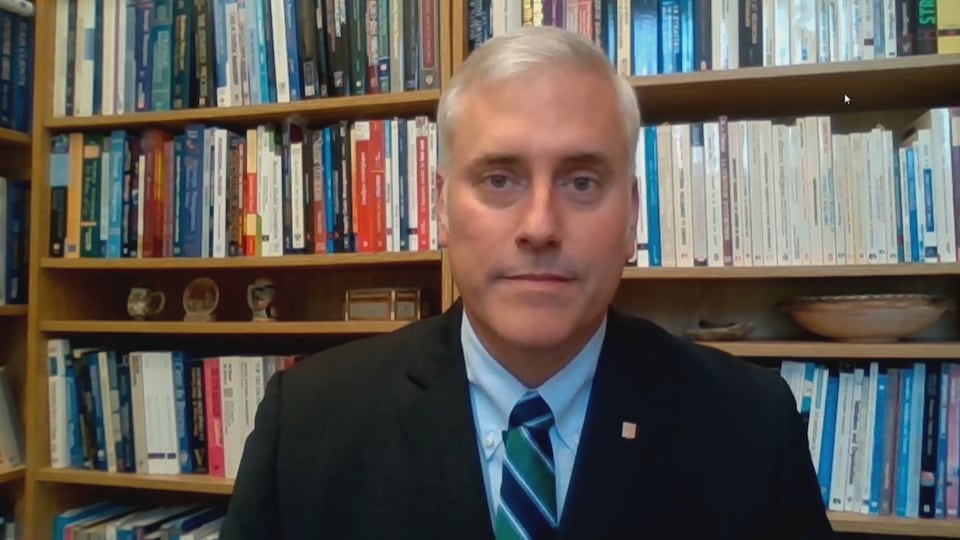 Le professeur Yan Cimon de l'Université Laval devant des étagères de livres.