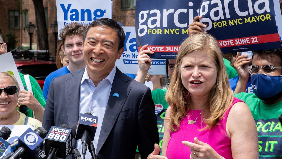 Junto com Andrew Yang, que está sorrindo, Catherine Garcia se dirige a uma multidão composta por seus apoiadores.