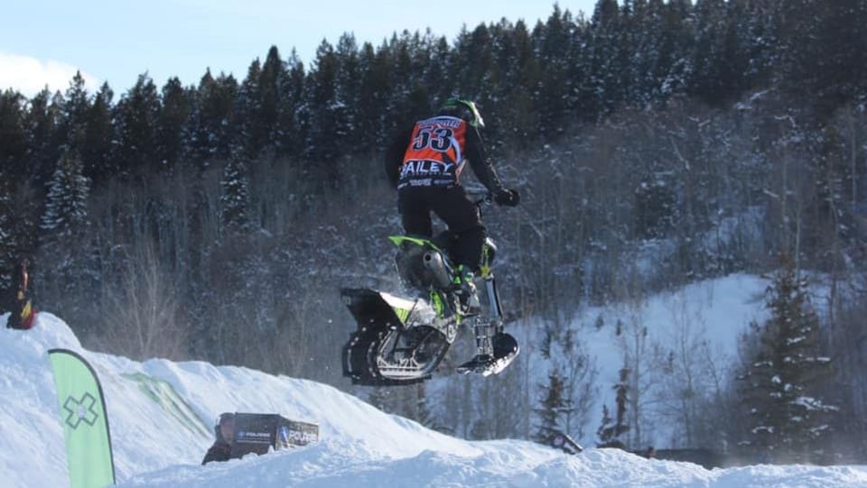 Un coureur de snow bike effectuant un saut.