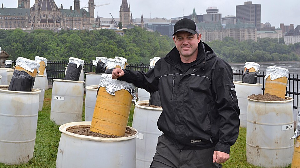Un homme posant aux côtés de matériel pyrotechnique, le Parlement du Canada en arrière-plan 