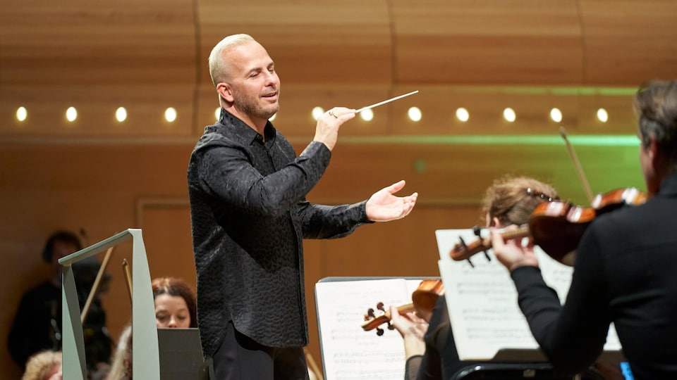 Le chef d'orchestre Yannick Nézet-Séguin donne le tempo sur scène devant les musiciens et musiciennes. 