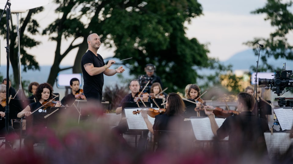 Le chef d'orchestre est debout devant ses musiciennes et musiciens.