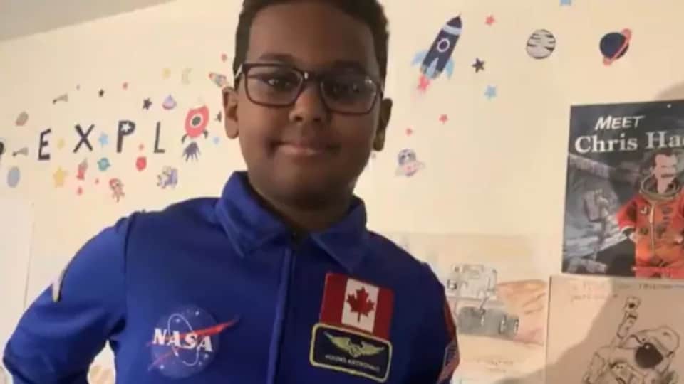 Photo d'un jeune garçon qui porte un polo avec un écusson de la NASA et un écusson en forme de drapeau du Canada.