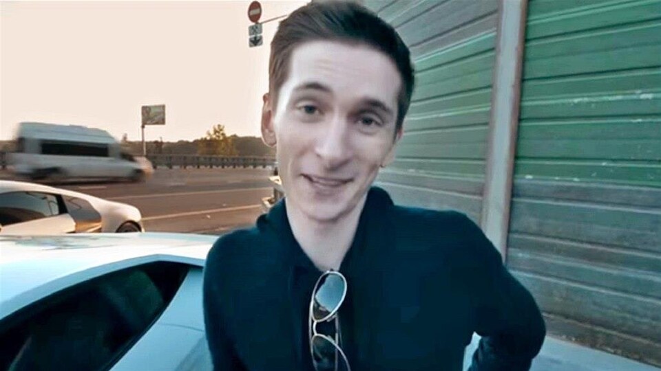 Yevgeniy Nikulin est devant la caméra. L'homme aux cheveux courts a des lunettes accrochées à son collet.