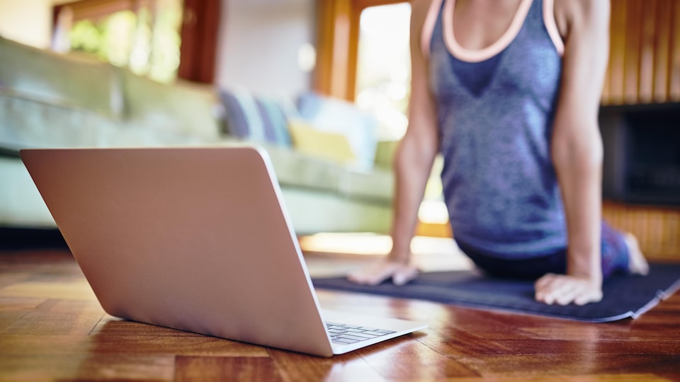 Une femme effectue un cours de yoga en ligne.