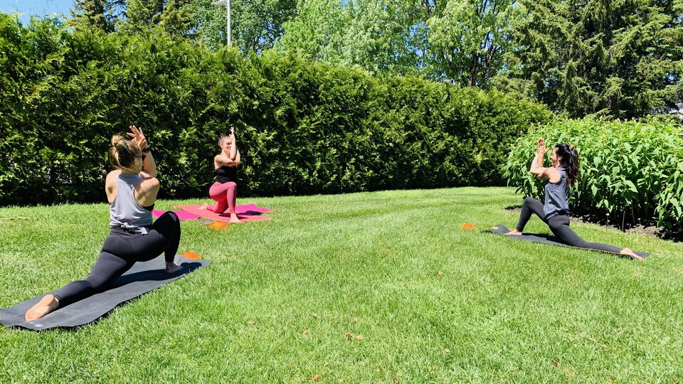 Trois femmes font du yoga dans un parc.