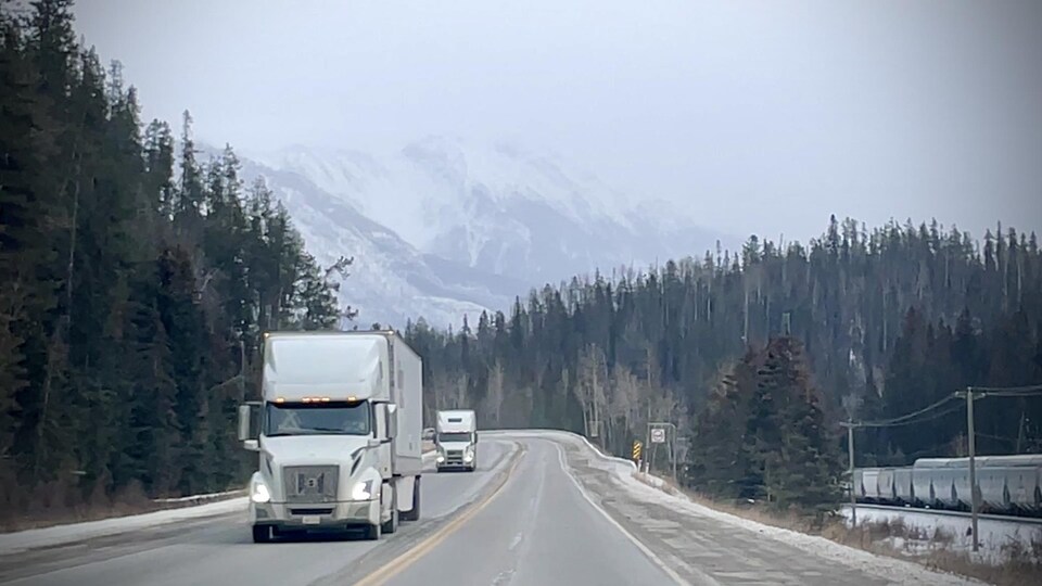 Deux camions circulent sur une route en montagne.