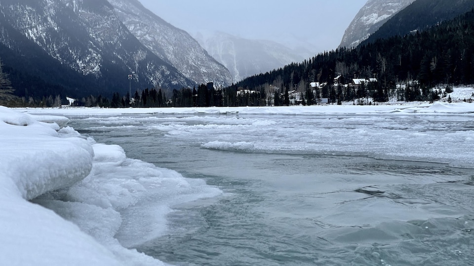 La rivière Kicking Horse bordée de neige et de glace dans un paysage de montagne.
