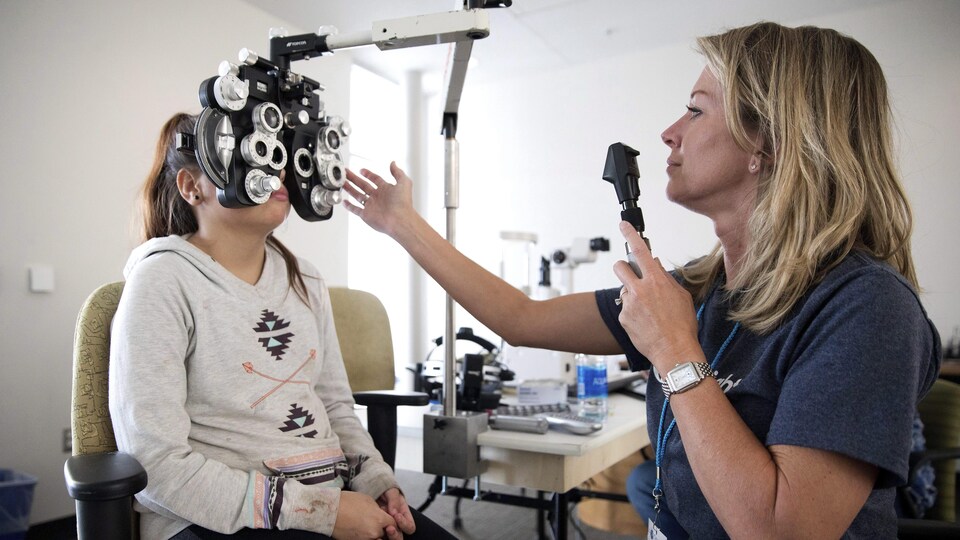 Une optométriste effectue un examen de la vue sur une jeune fille.