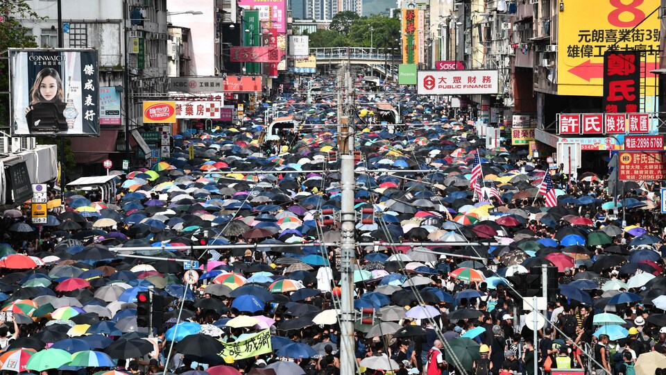 Une rue est bondée de manifestants tenant des parapluies.