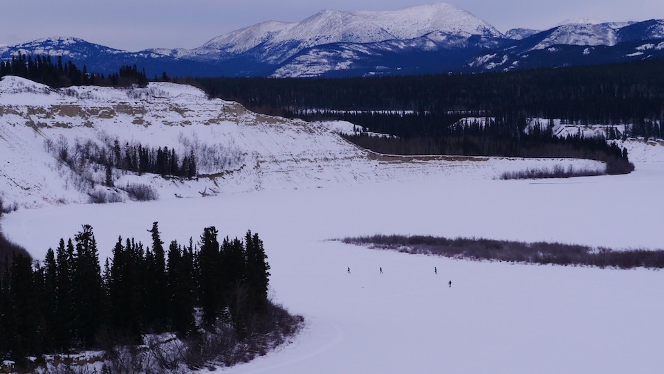 Des participants sur la piste vus de loin avec le paysage de montagnes en arrière-plan.