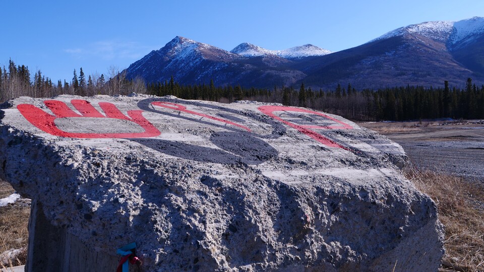 Du ciment avec des symboles en peinture et des montagnes enneigées en arrière-plan.