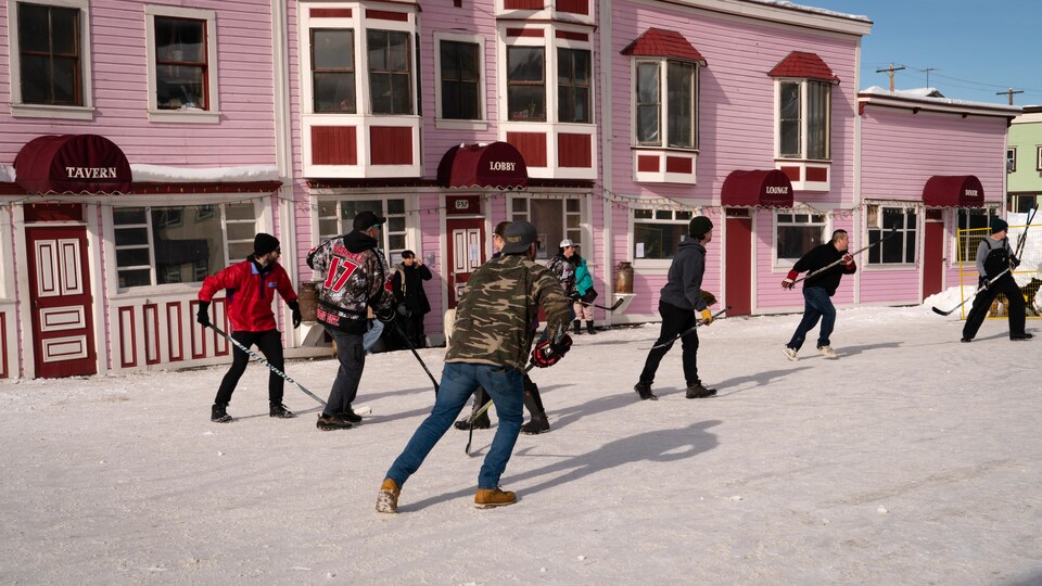 Des gens jouent au hockey dans la rue devant l'hôtel Westminster de Dawson, le 18 mars 2023. 