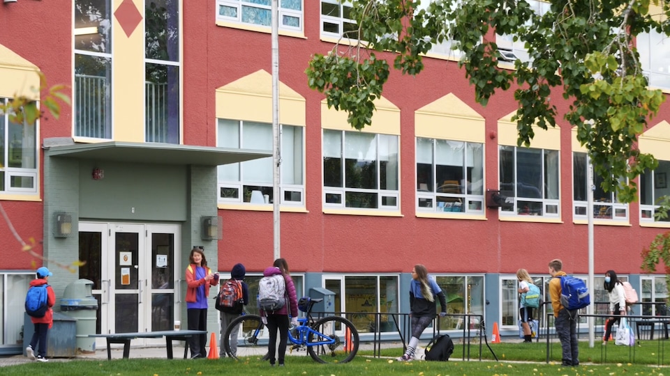 Des élèves et du personnel devant une école.