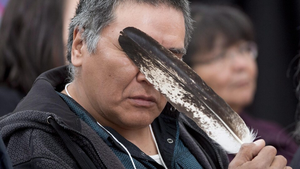 Un homme cache ses yeux derrière une plume d'aigle