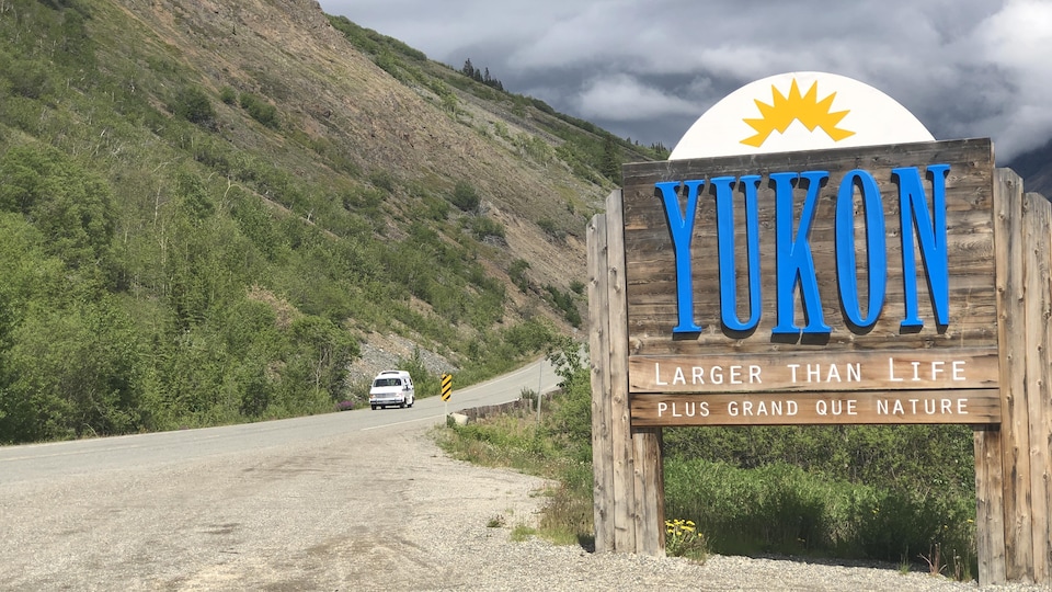 Enseigne montrant la frontière du Yukon avec un véhicule qui passe sur la route.