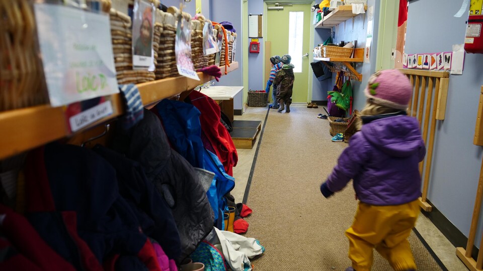 Un enfant court dans un couloir vers d'autres enfants.