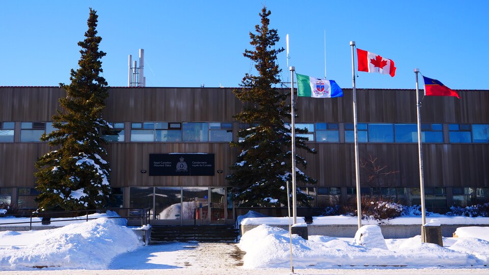 Façade d'un édifice en hiver avec des drapeaux qui flottent au vent.