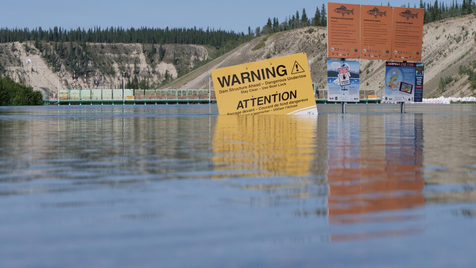 Des pancartes d'avertissement à moitié submergées dans l'eau.