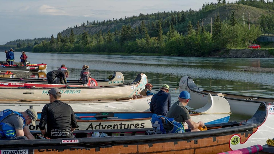 Des personnes sur des canoes au bord d'une rivière.